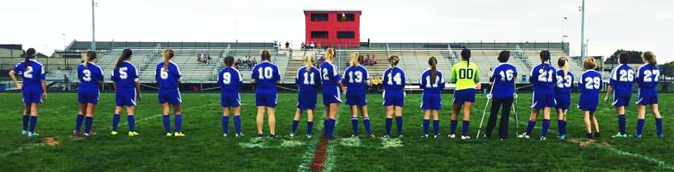 The players of the 2014 Lady Blue Lions Soccer Team lined up on a soccer field 
                    after the starting roster has been announced for the fall tournament game